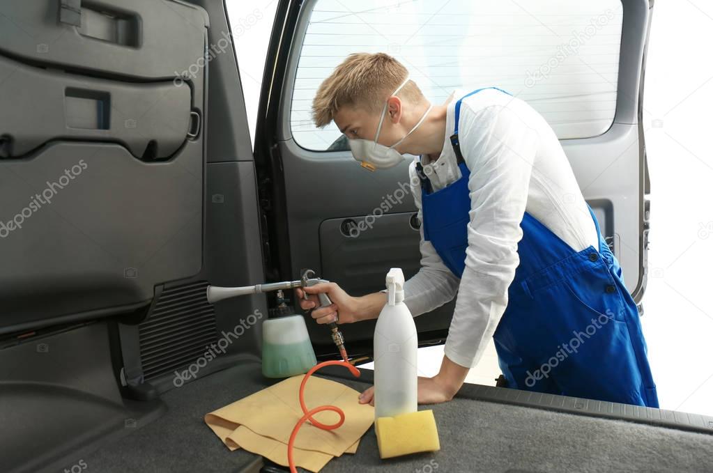 Young man cleaning car salon in body shop