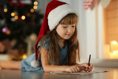 Sevimli kız evde Noel Baba'ya mektup yazma Noel şapkalı