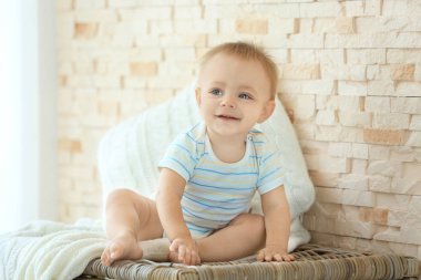 Hasır kutu yakınındaki duvara oturan şirin bebek