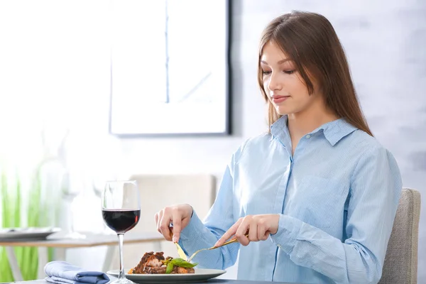 Mladá žena jíst vynikající žebra v restauraci — Stock fotografie