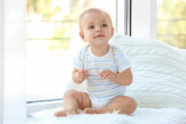 Cute little baby sitting on window sill at home — Stock Photo, Image