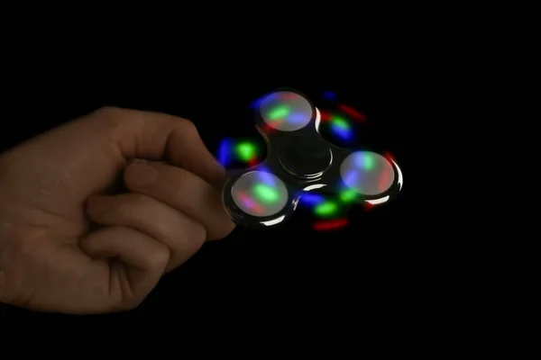 Man rolling modern luminous spinner on dark background — Stock Photo, Image