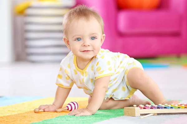 Schattige kleine baby spelen met muziekinstrument thuis — Stockfoto