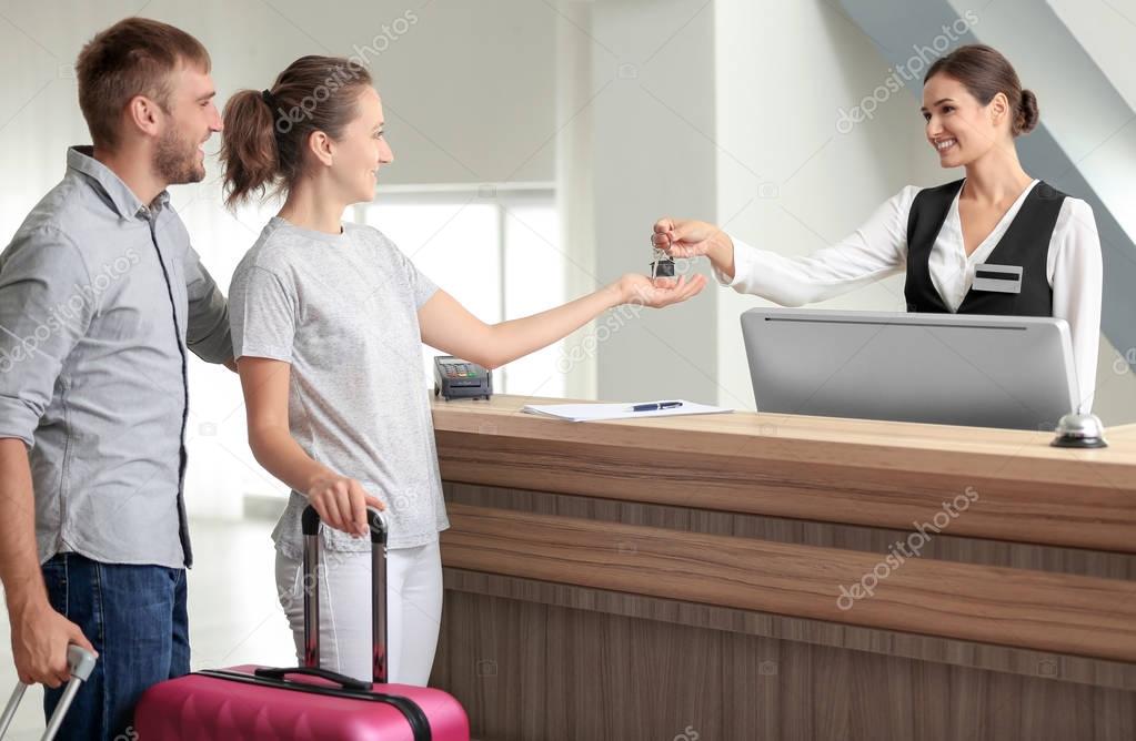 Young couple receiving key from hotel room at reception
