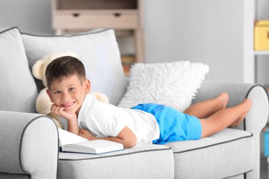 Evde kitap okuyan şirin bir çocuk.