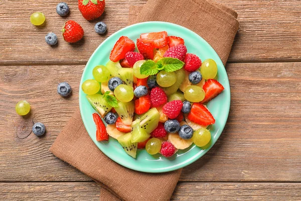 Plate with fruit salad on wooden table — Stock Photo, Image