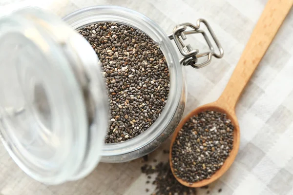 Chia seeds in jar and spoon on table — Stock Photo, Image