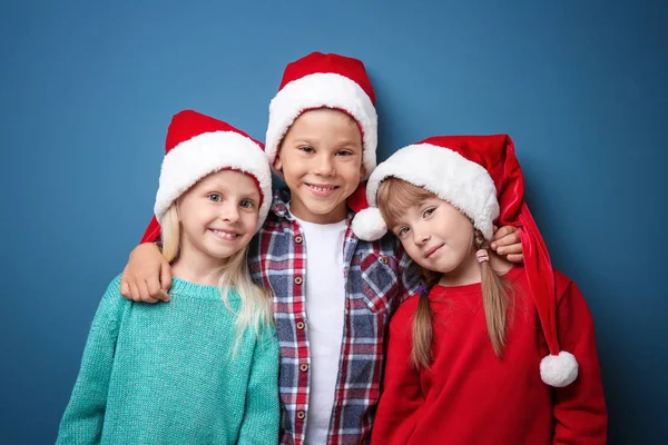 Słodkie dzieci w Santa kapelusze na kolor tła. Boże Narodzenie koncepcja — Zdjęcie stockowe