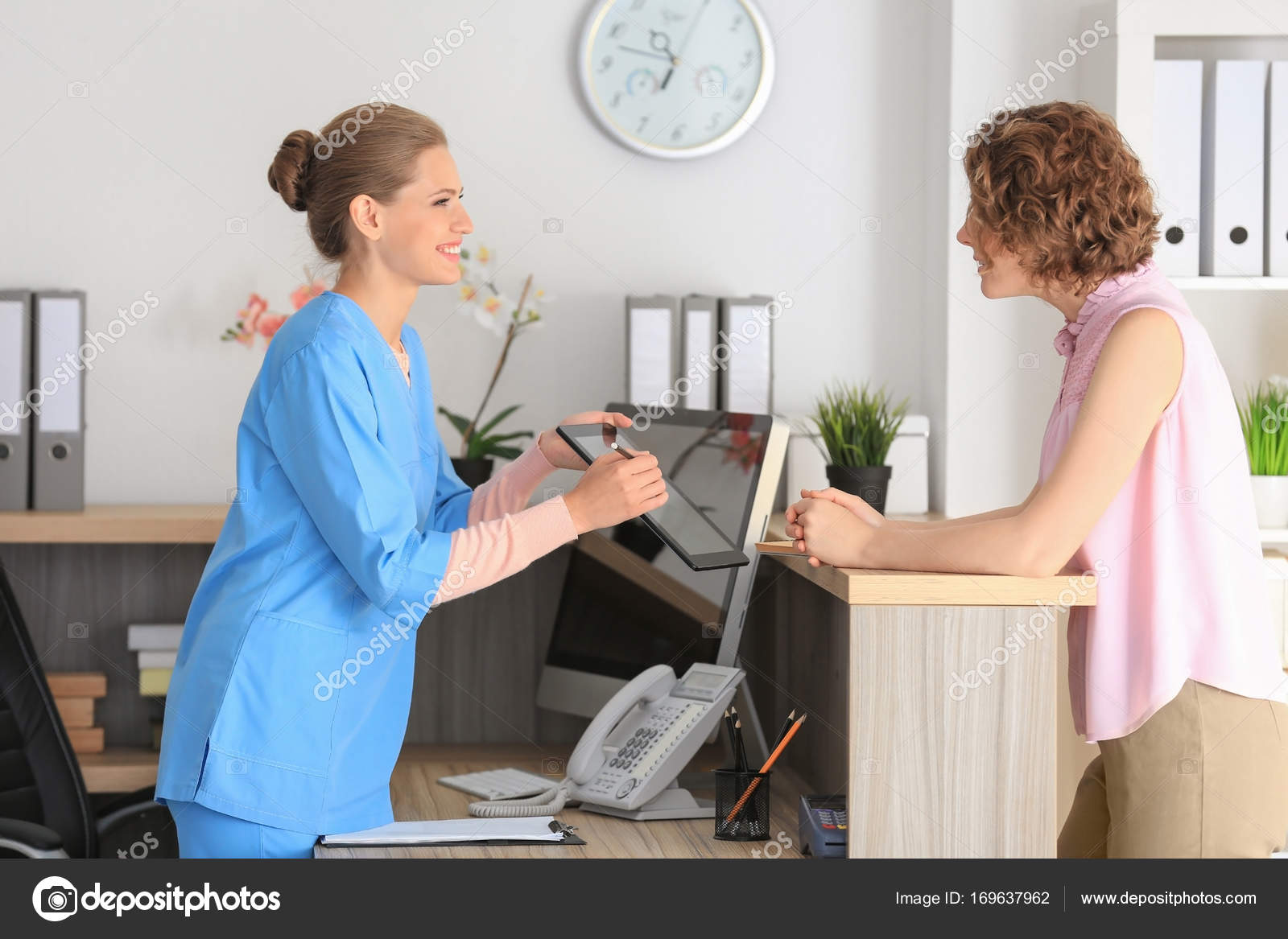Young Female Receptionist With Client In Hospital Stock Photo