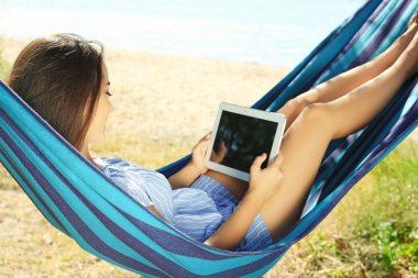 Tablet bilgisayar açık havada hamakta rahatlatıcı çekici kadın