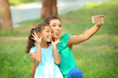 Sevimli küçük kız ve annesi selfie Park'ta güneşli günde alarak.