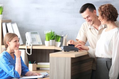 Hastanede istemcilerle genç kadın resepsiyonist