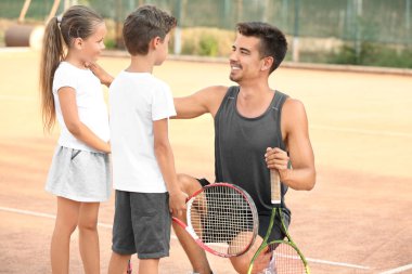 Tenis kortunda Küçük çocuklu genç eğitmeni
