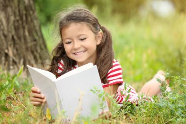 Kitap okuyan sevimli küçük bir kız. 