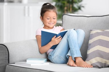 Kitap okuyan sevimli küçük bir kız. 