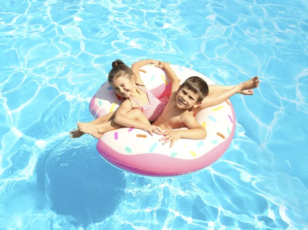 Söta barn på uppblåsbar ring i poolen — Stockfoto