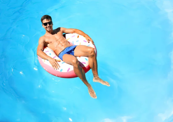 Junger Mann auf aufblasbarem Donut — Stockfoto