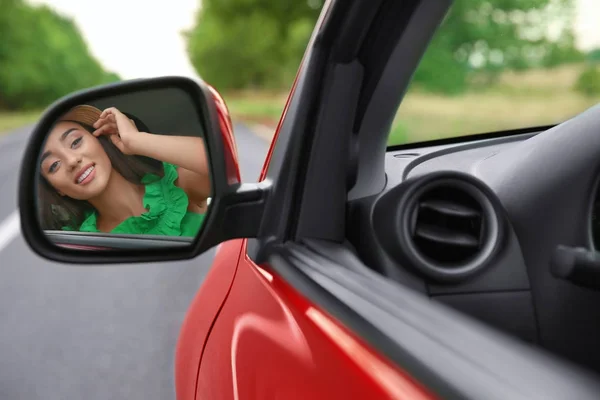 Молодая женщина смотрит в зеркало заднего вида автомобиля — стоковое фото