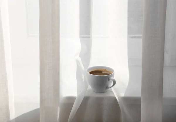 Cup of coffee on window sill — Stock Photo, Image