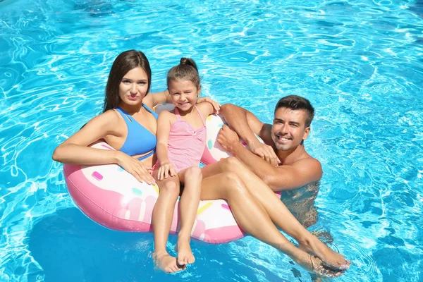 Young couple and cute daughter with inflatable ring in swimming pool — Stock Photo, Image
