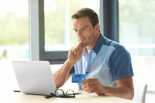 Jovem segurando cartão de crédito ao usar laptop em casa — Fotografia de Stock
