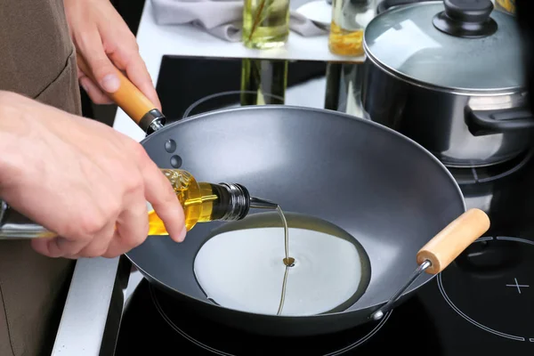 Man koken olie uit de fles te gieten in de koekenpan — Stockfoto