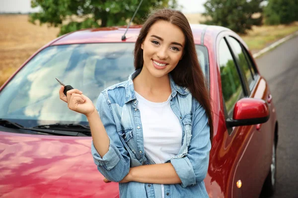 Jeune femme avec clé près de voiture neuve — Photo