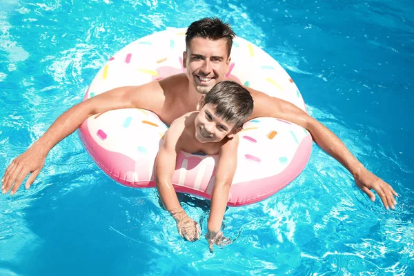 Bell'uomo e figlio carino con anello gonfiabile in piscina — Foto Stock
