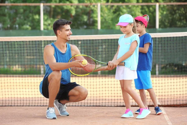 Mladého trenéra s malými dětmi na tenisový kurt — Stock fotografie