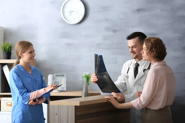 Recepcionista e médico com cliente no hospital — Fotografia de Stock