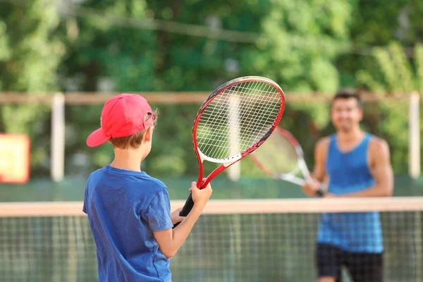 Mladého trenéra s malého chlapce hrát tenis na kurtu — Stock fotografie