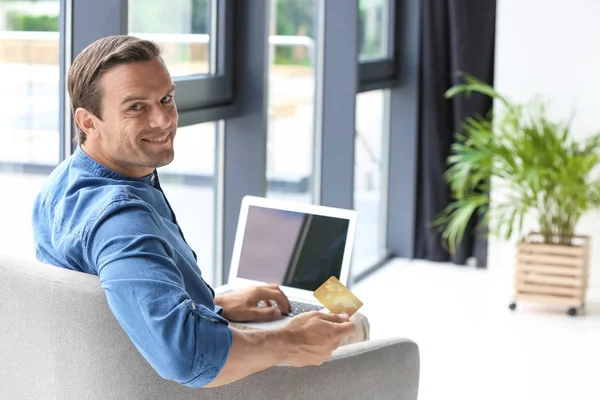 Junger Mann mit Kreditkarte, während er zu Hause Laptop benutzt — Stockfoto