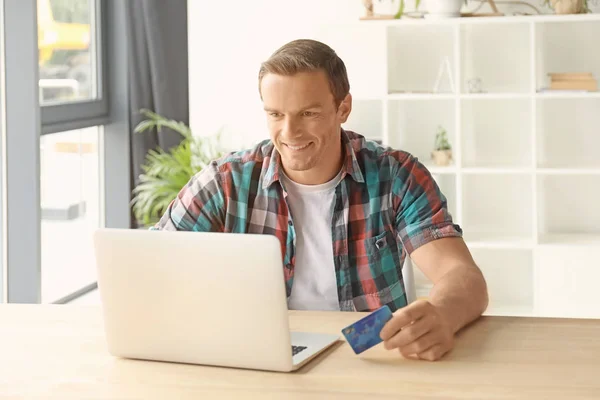 Junger Mann mit Kreditkarte, während er zu Hause Laptop benutzt — Stockfoto