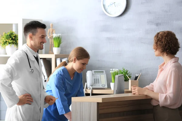 Receptionist och läkare med klienten på sjukhus — Stockfoto