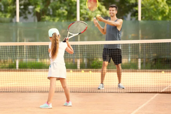 Young trainer with little girl playing tennis on court — Stock Photo, Image