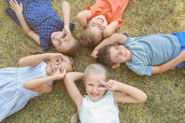 Groep kinderen liggend op groen gras in park — Stockfoto