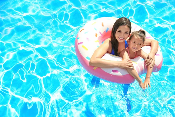 Mulher nova e filha bonito com anel inflável na piscina — Fotografia de Stock