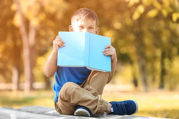 Söt liten pojke läsebok i park — Stockfoto