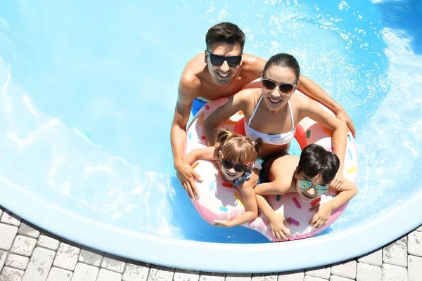 Famille heureuse avec beignet gonflable dans la piscine — Photo