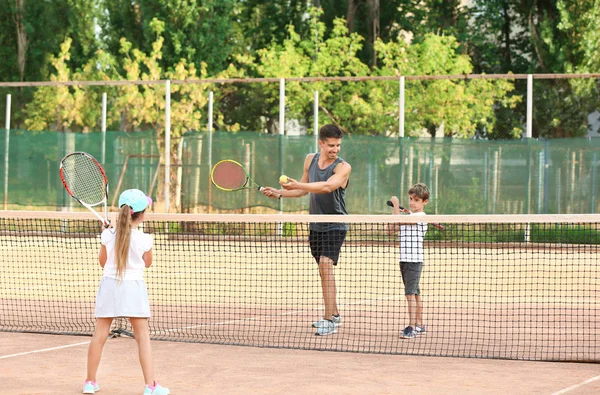 Sahada Tenis oynarken Küçük çocuklu genç eğitmeni