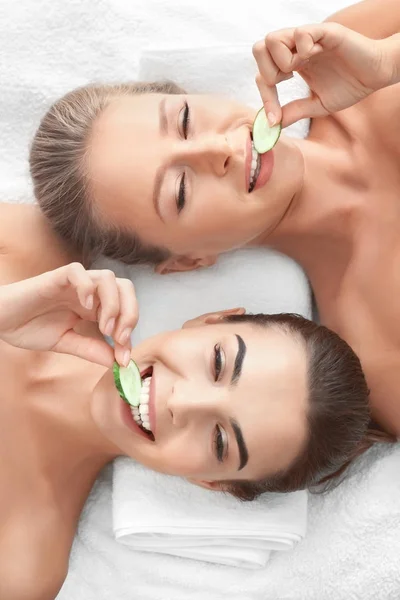 Jonge vrouwen met plakjes komkommer in spa salon — Stockfoto