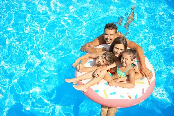 Famiglia felice con anello gonfiabile rilassante in piscina — Foto Stock