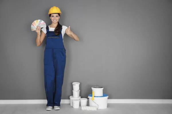 Kvinnliga dekoratör holding färgpalett prover nära grå vägg — Stockfoto