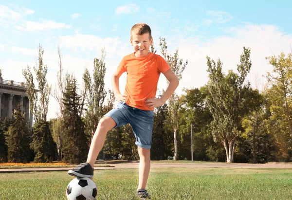 Симпатичный мальчик с футбольным мячом на лужайке — стоковое фото