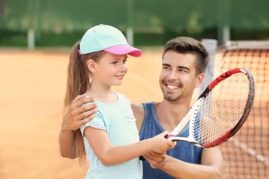 Tenis kortunda küçük kızla genç eğitmeni