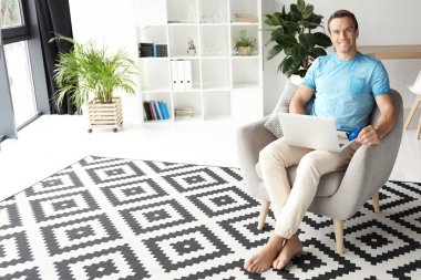 Kredi kartı dizüstü evde kullanırken tutan genç adam