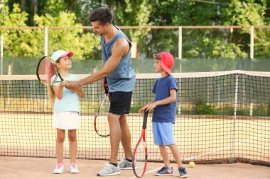 Tenis kortunda Küçük çocuklu genç eğitmeni