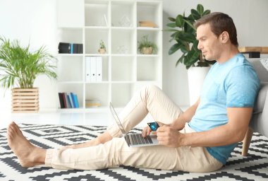 Kredi kartı dizüstü evde kullanırken tutan genç adam