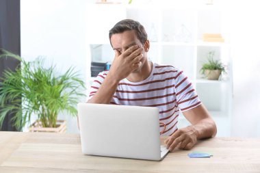 Genç adam evde dizüstü bilgisayar kullanıyor.