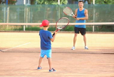 Küçük çocuk tenis kortunda oynamaya ile genç eğitmeni